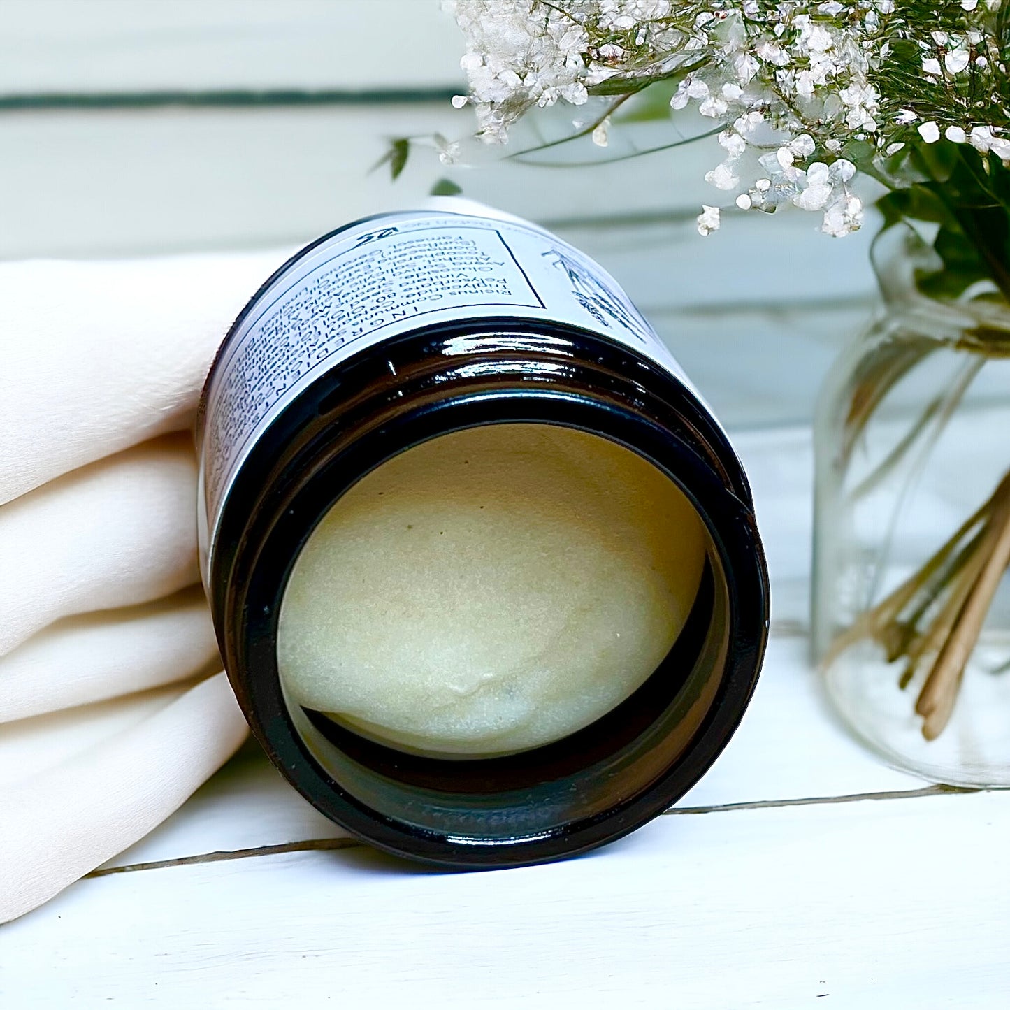 showing an open glass jar of cleaning balm made with oats with lavender and rose Damascena essential oils made by buddha and bubbles botanicals