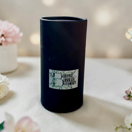 Black cylindrical container with a label on a light surface with flowers