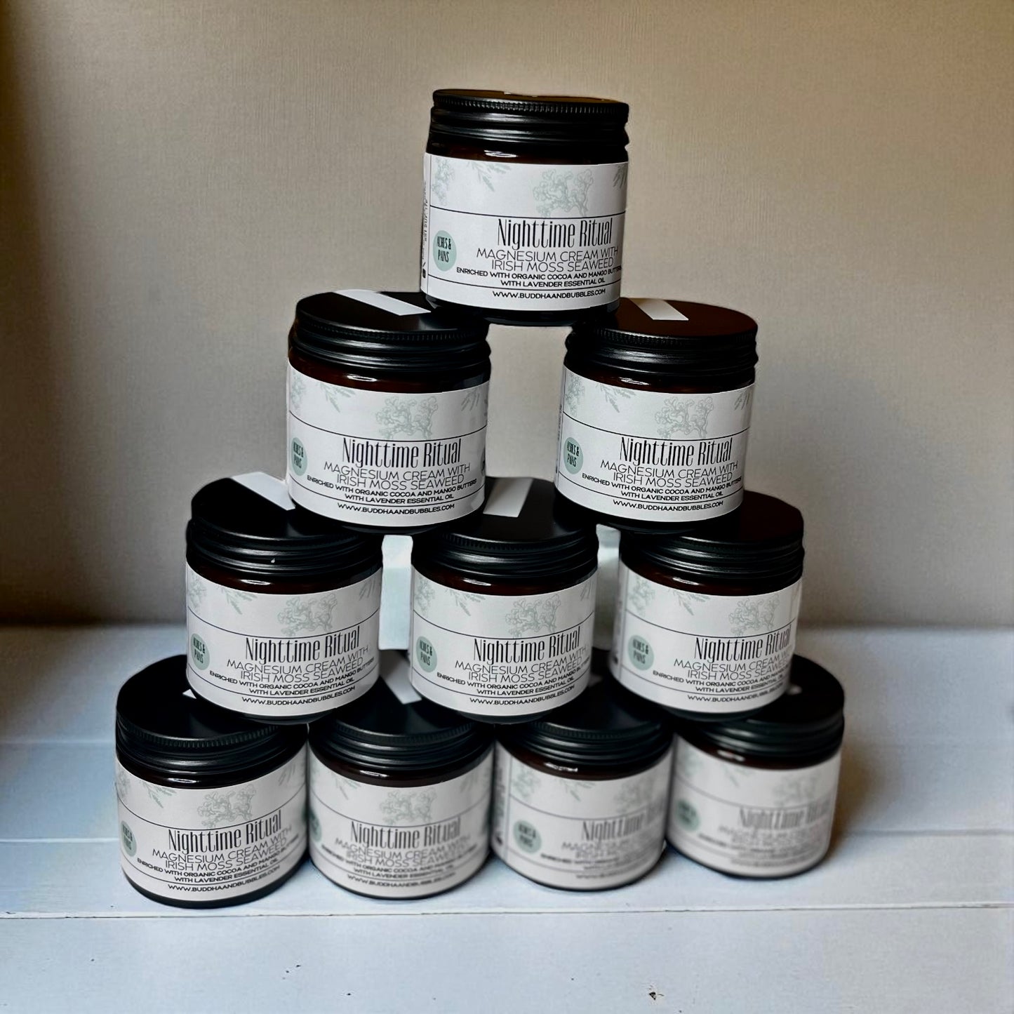 Pyramid of Nighttime Ritual Seaweed magnesium cream jars with black lids on a white surface.