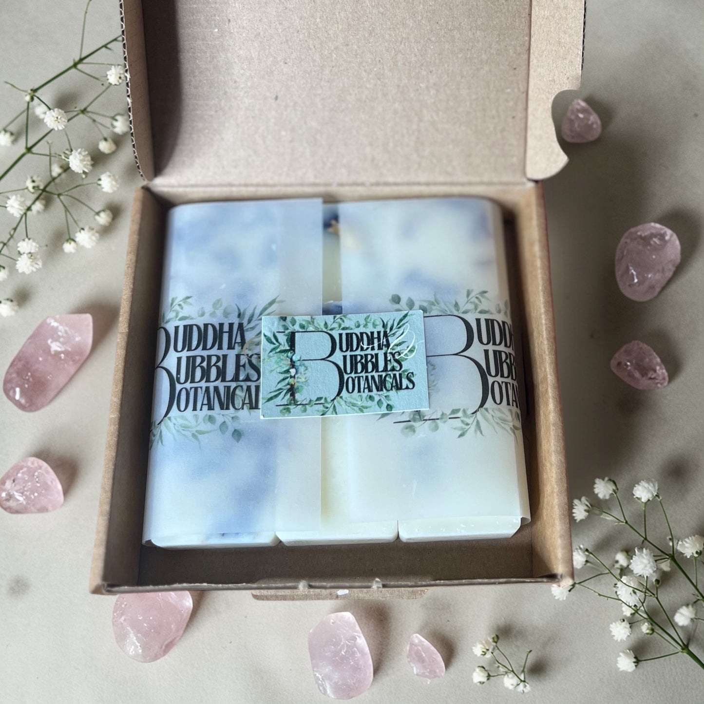 Buddha Bubbles Botanicals essential oil wax melts in a box with pink crystals and flowers on a light background