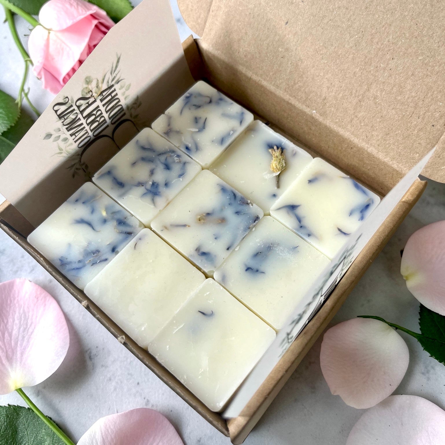 Box of essential oil wax melts with floral decorations on a light background