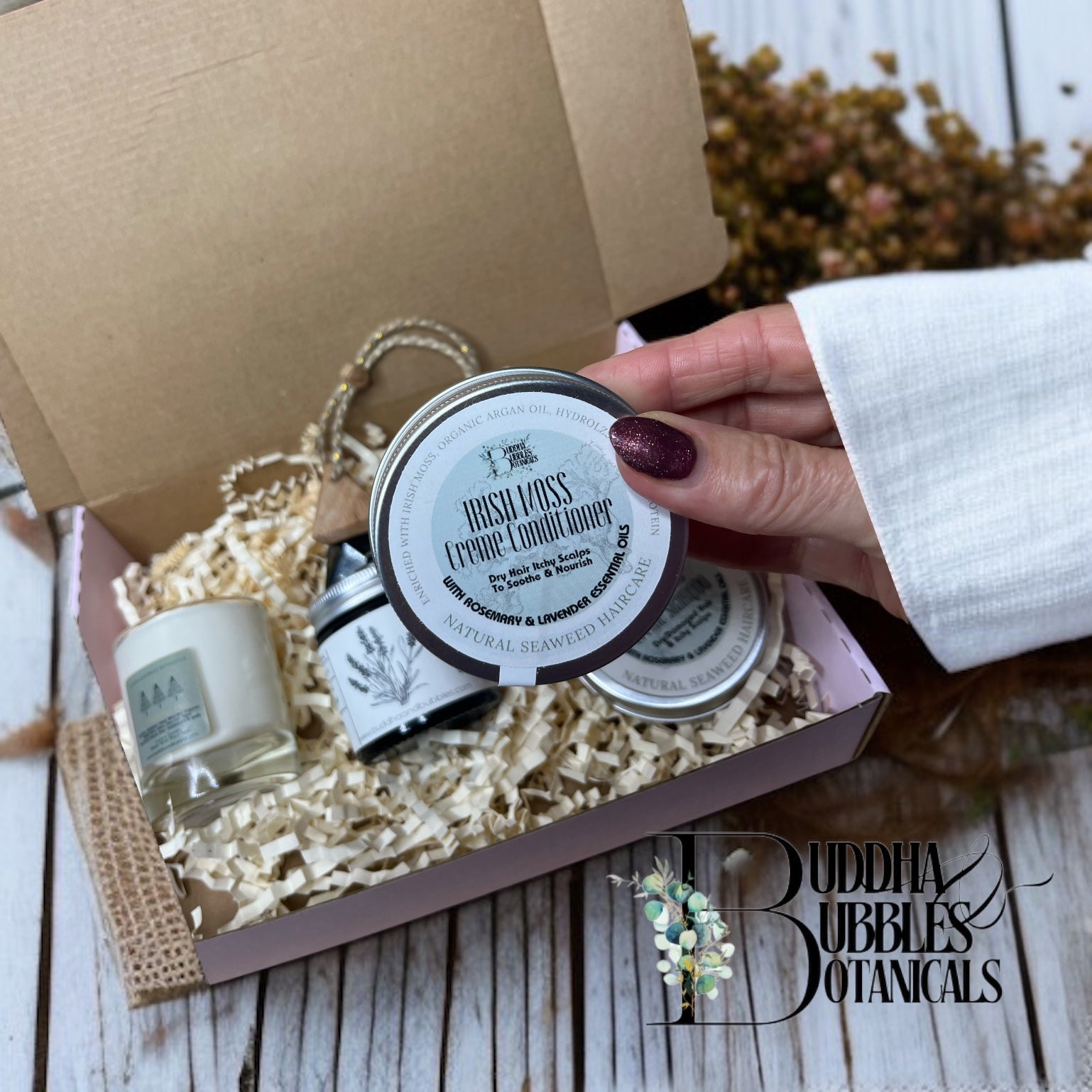 xmas gift box with hand holding a tin of seaweed shampoo product in a box of Buddha Bubbles Botanicals branding in the background