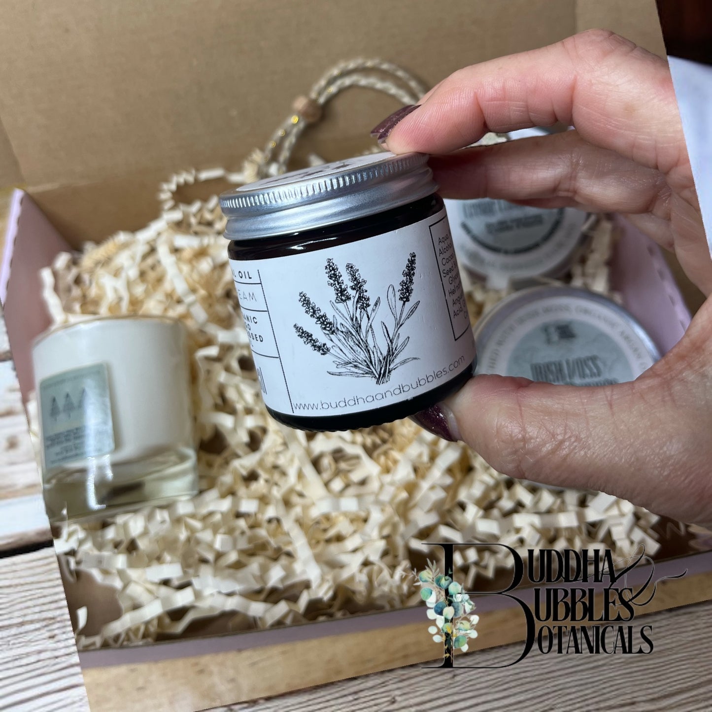xmas gift box with hand holding a jar of magnesium cream labelled with Buddha Bubbles Botanicals branding in a gift box i