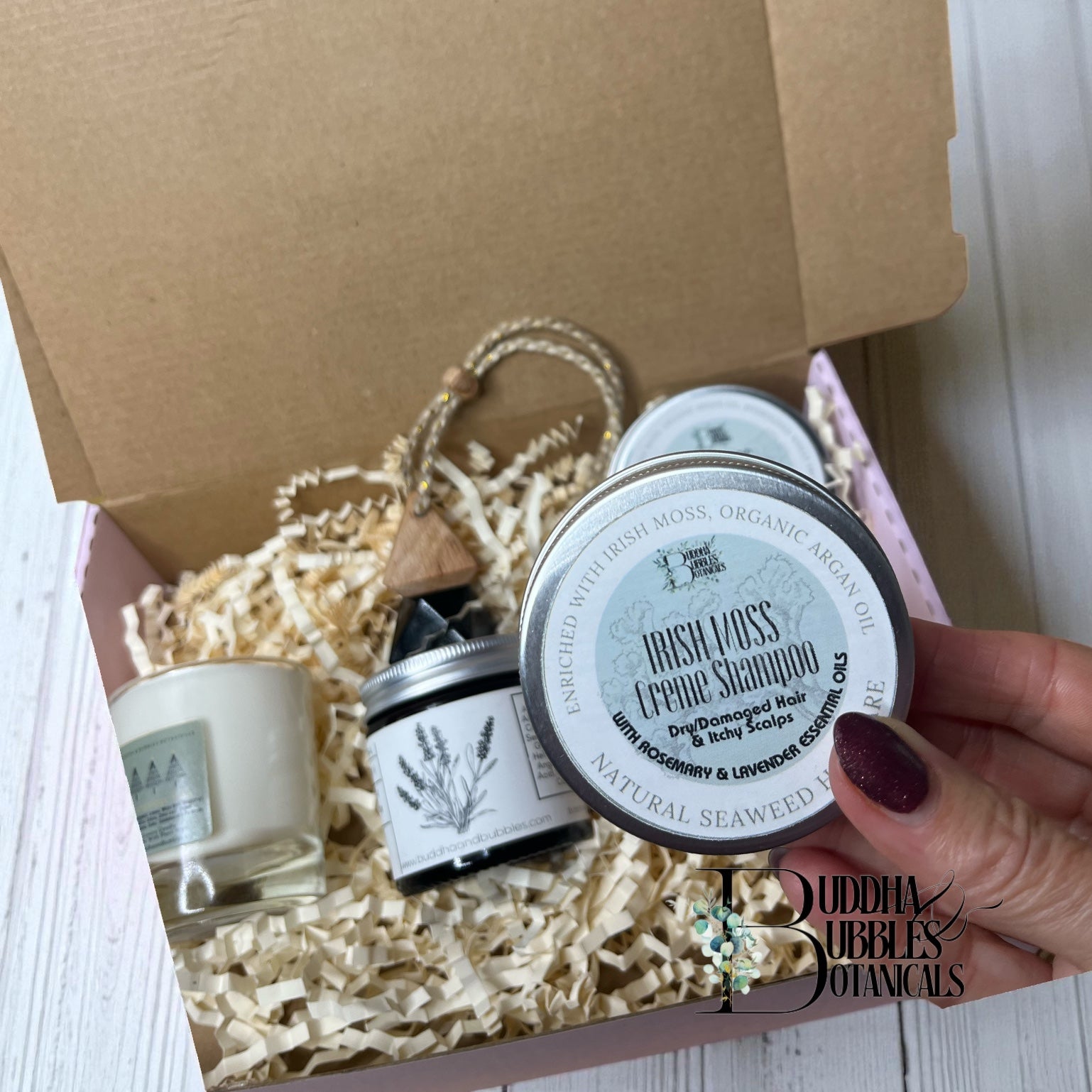 Hand holding an Irish Moss Creme shampoo product with a box of beauty products in the background