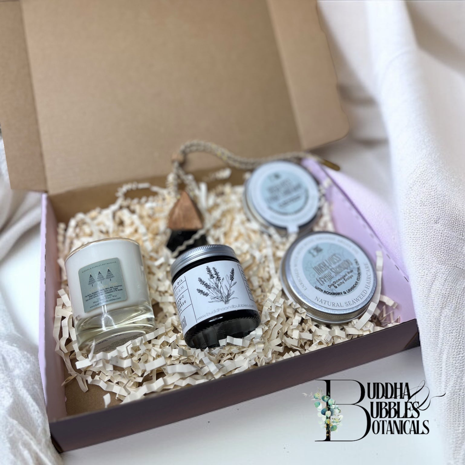 Candle in a jar in a box with magnesium cream, car air freshener and seaweed shampoo and conditioner 'Buddha Bubbles Botanicals' branding.