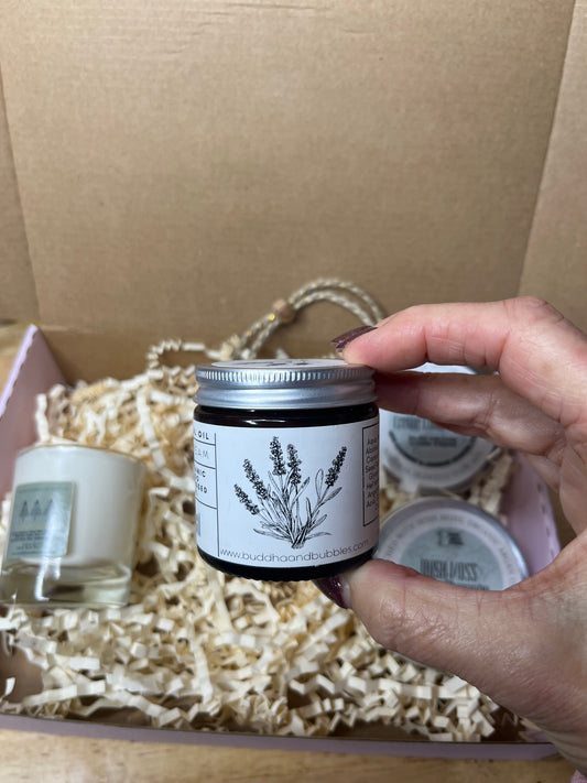 Hand holding a black container of magnesium cream for restless legs aches and pains muscle cramps  against a white background