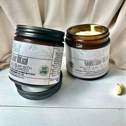 Two jars of 'Nighttime Ritual' magnesium cream on a light wooden surface with a beige fabric background made by buddha and bubble botanicals