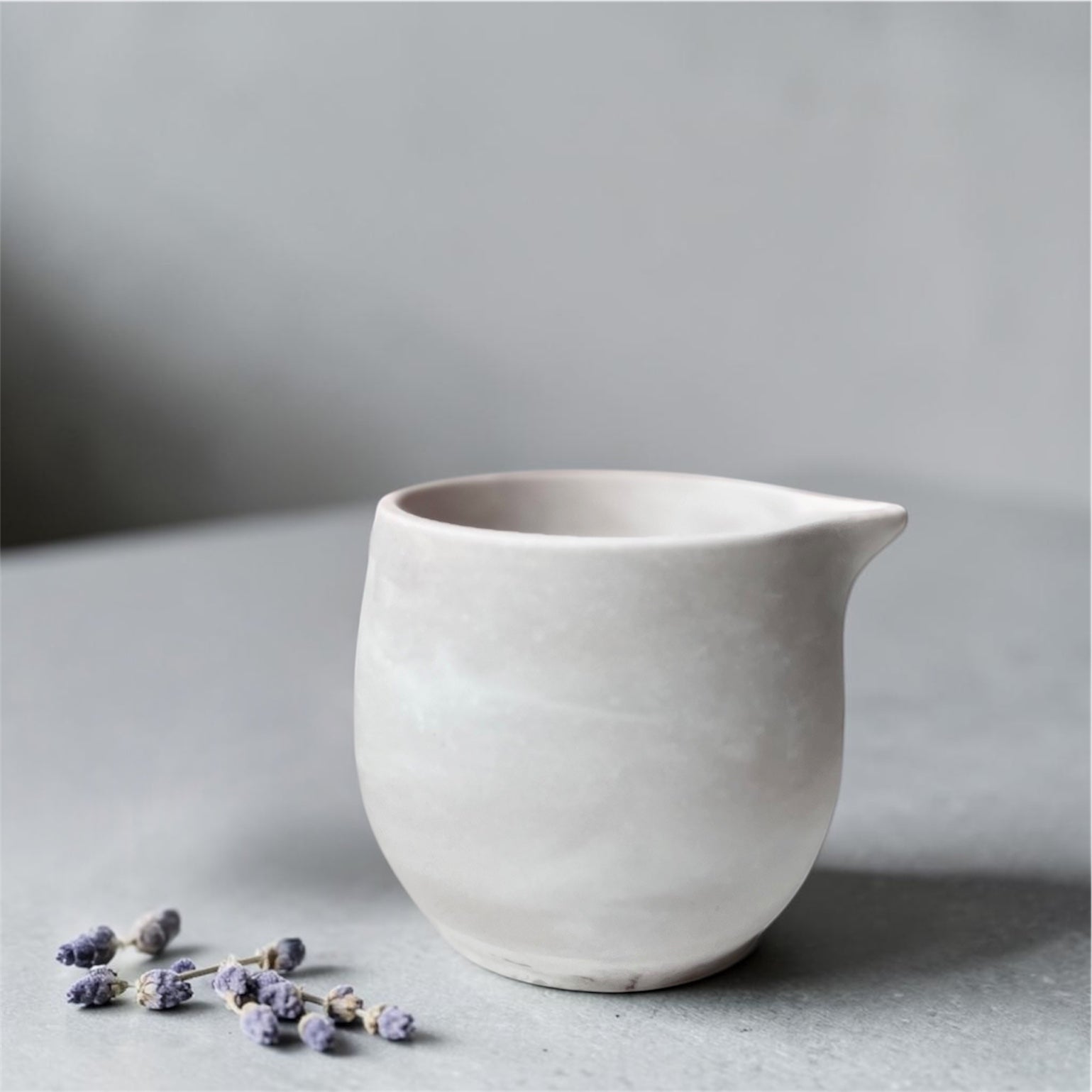 White eco resin massage candle on a grey surface with a soft focus background
