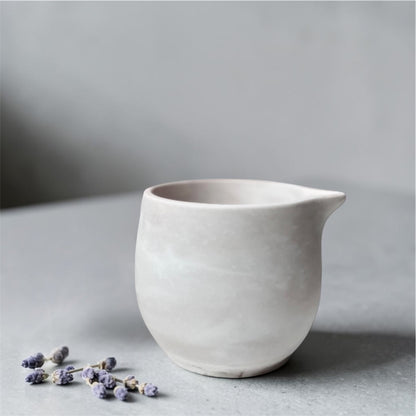 White eco resin massage candle on a grey surface with a soft focus background