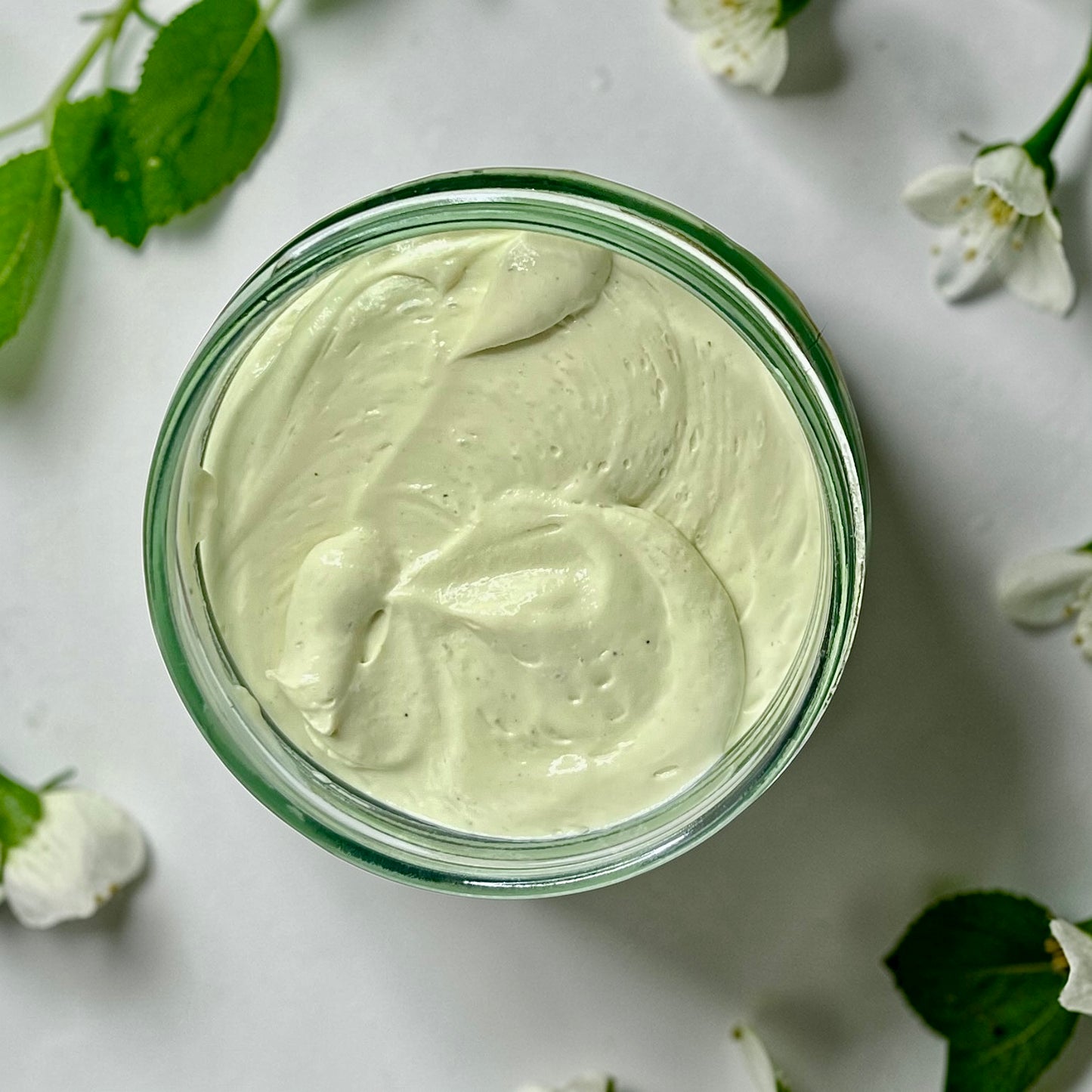 jumbo Jar of magnesium cream placed on a soft white surface with flowers