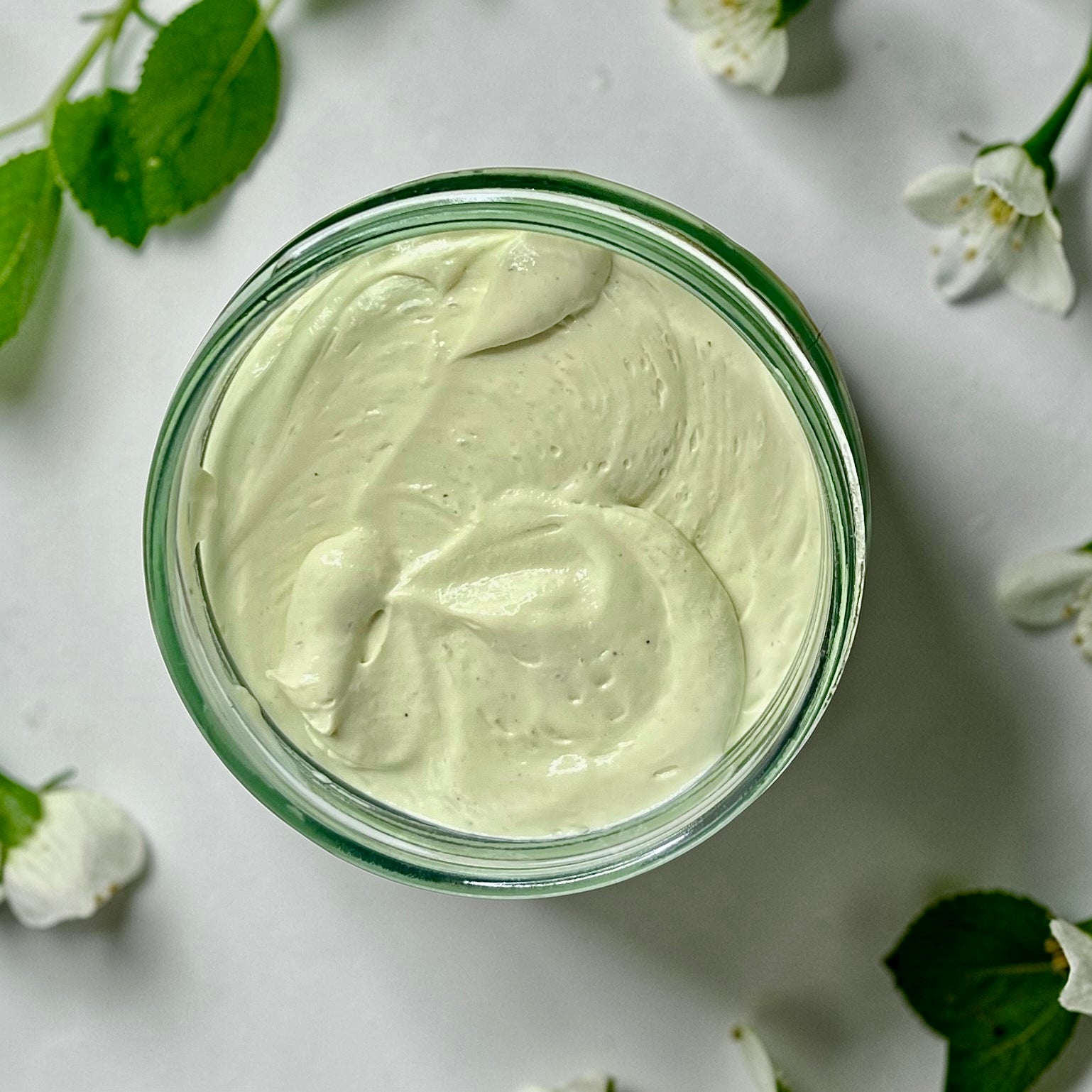 jumbo Jar of magnesium cream placed on a soft white surface with flowers