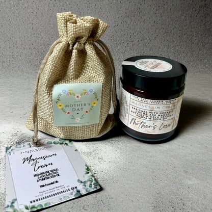 Jar of mothers love magnesium cream with a burlap bag and card on grey surface