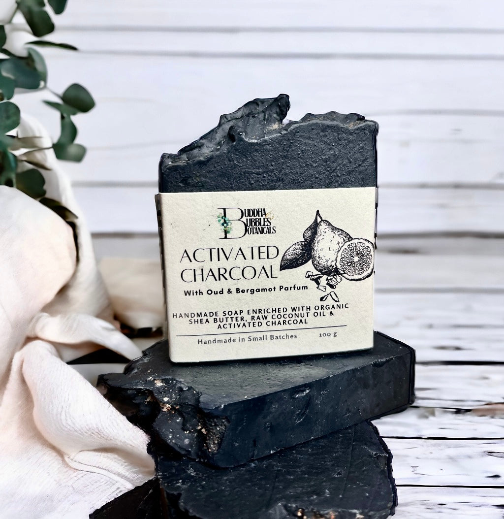 Soap bar exfoliating with activated charcoal, oud and bergamot parfum on wooden table
