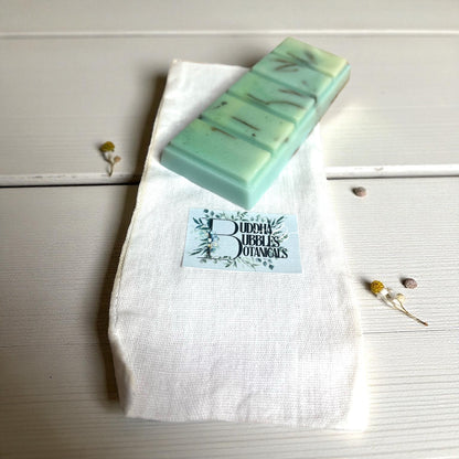Green wax melt snap  bar on a white cloth with 'Buddha Bubbles Botanicals' branding on a wooden surface.