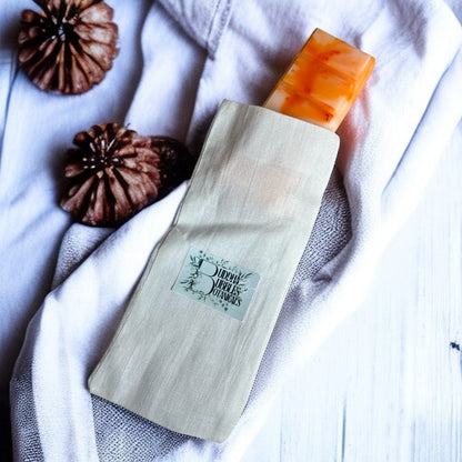 Wax melt snap bar in cotton reusable bag on a white fabric background