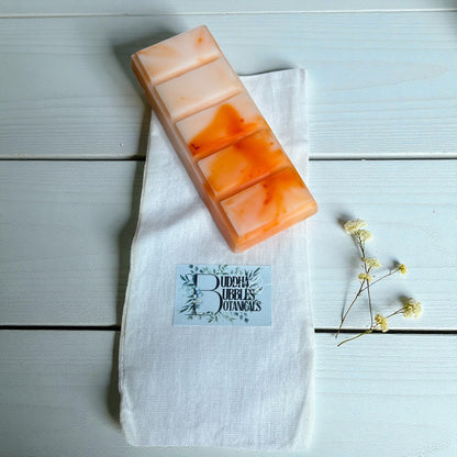 Gradient wax melt snap bar on a white cotton bag with a brand label, on a light wooden surface.
