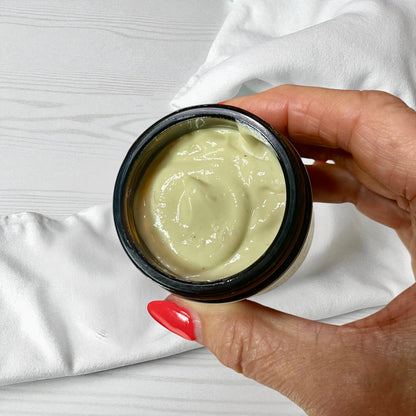 Hand holding a jar of Irish moss magnesium cream against a white background