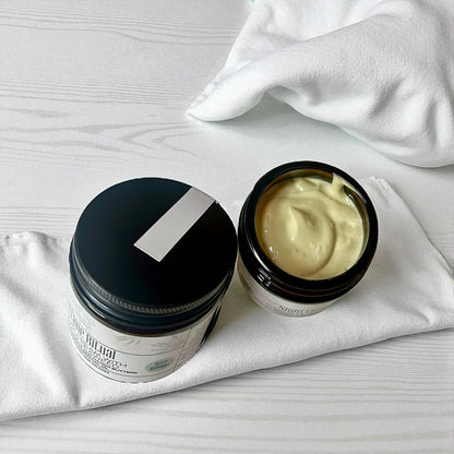 Two jars of magnesium cream one with lid off with Irish moss seaweed  on a white surface 