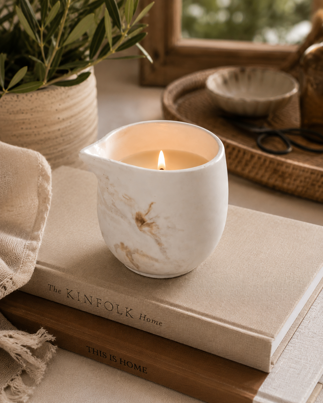 eco resin massage candle with a lit candle on a book, surrounded by natural elements.
