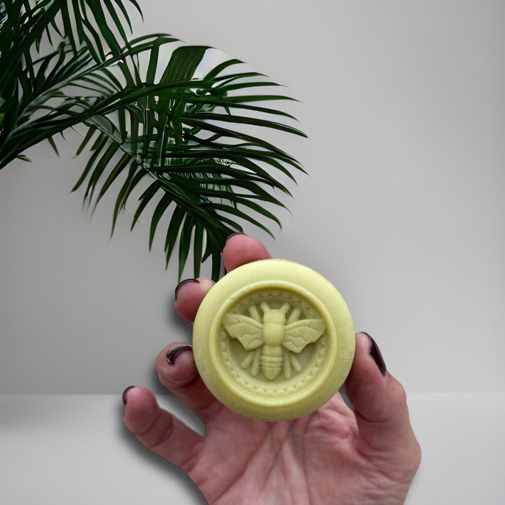solid moisturising butter bar for the body held in a hand with bee design