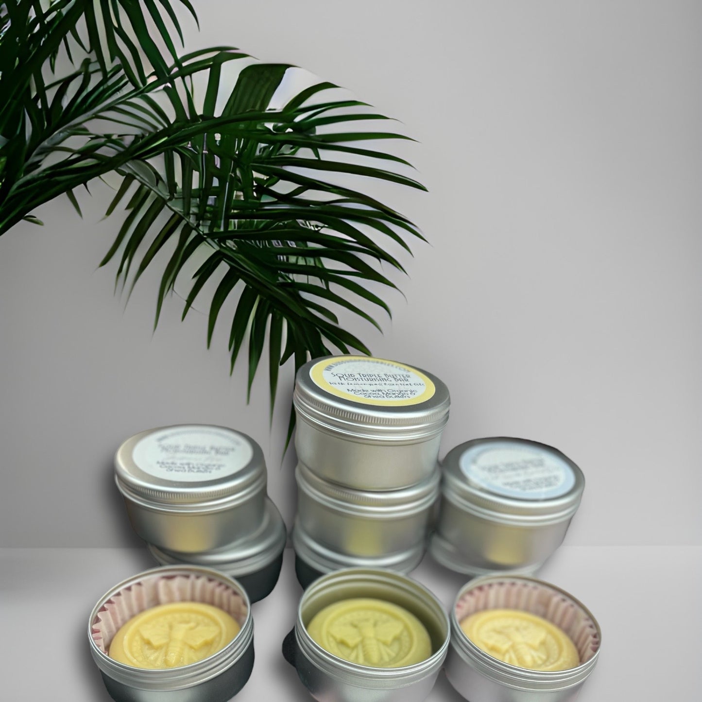 solid moisturising butter bar for the body held in a hand with bee design in aluminium tins